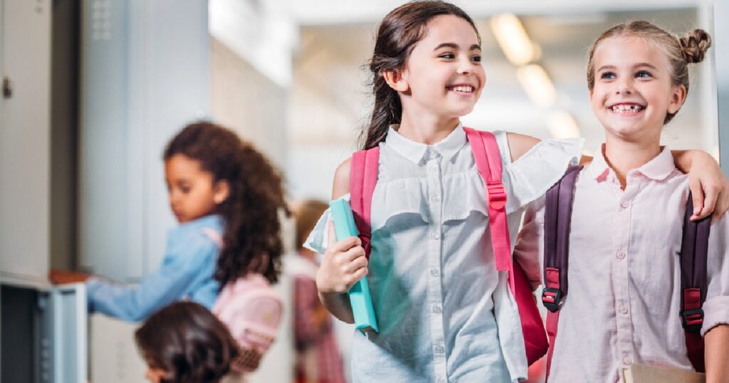 Two girls walking with backpacks at school